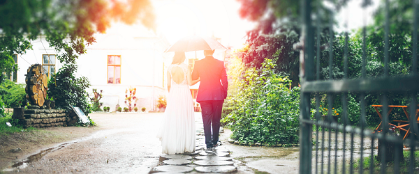 A couple walking under a wedding umbrella