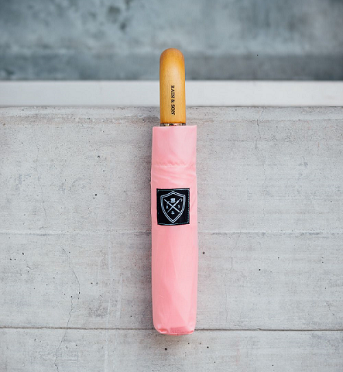 Light pink umbrella hanging on a brick wall. 